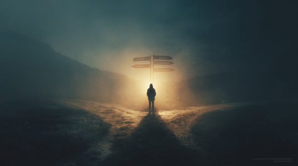 A person standing at a crossroad with a guiding light.